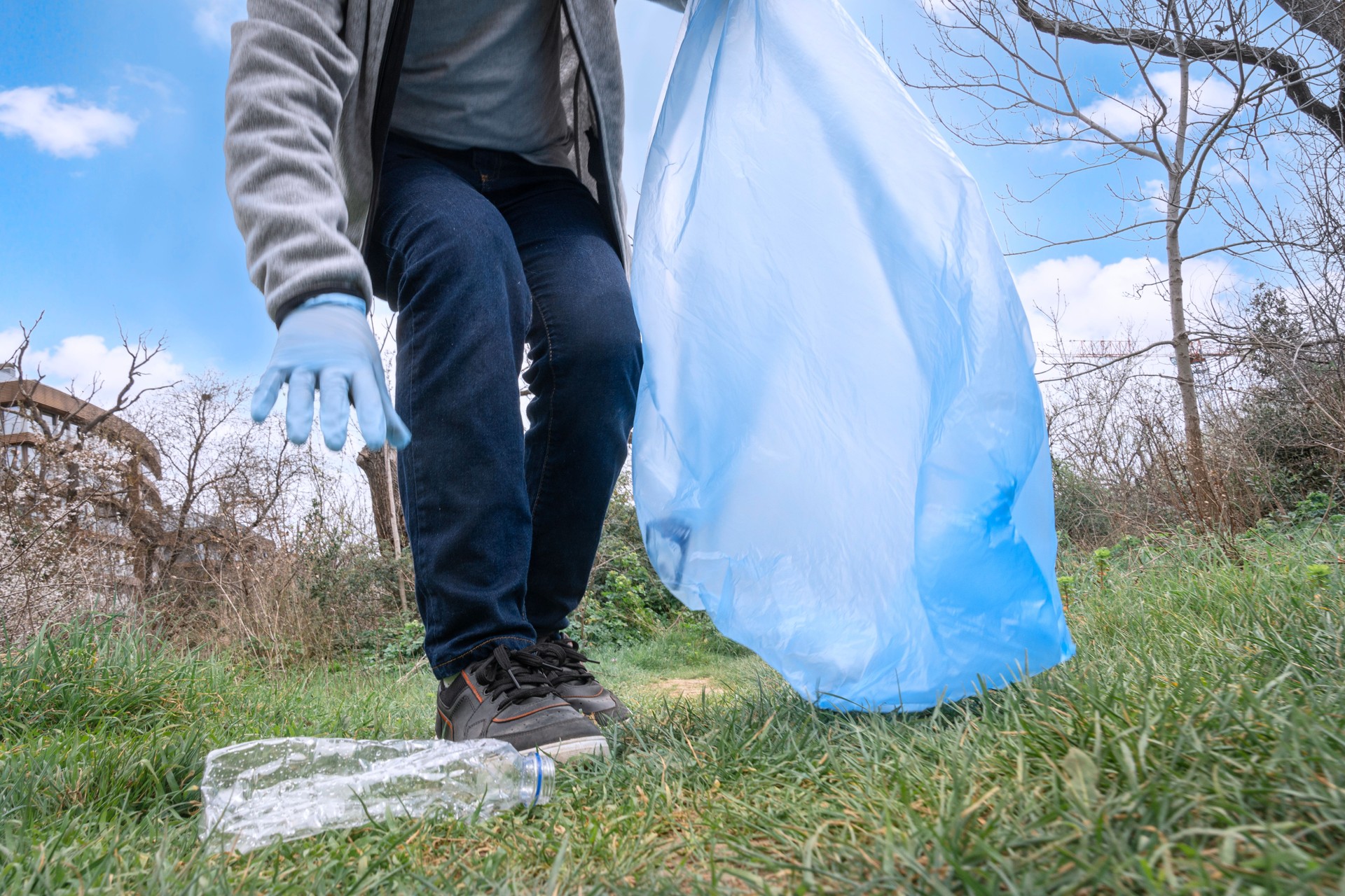 Volunteer picking up plastic bottle in a park during a cleanup