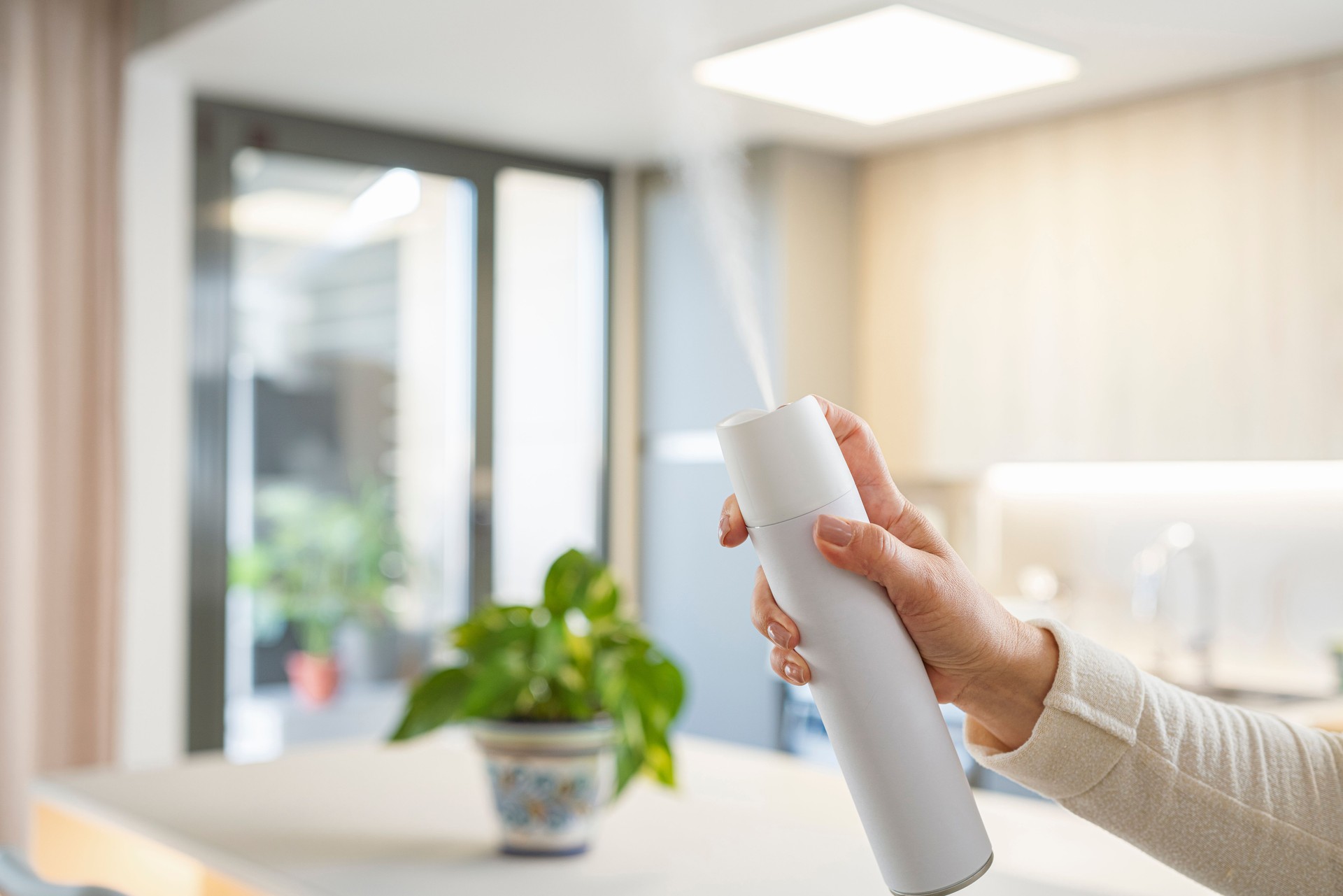 Woman's hand holding air freshener can to remove unpleasant odors of the kitchen